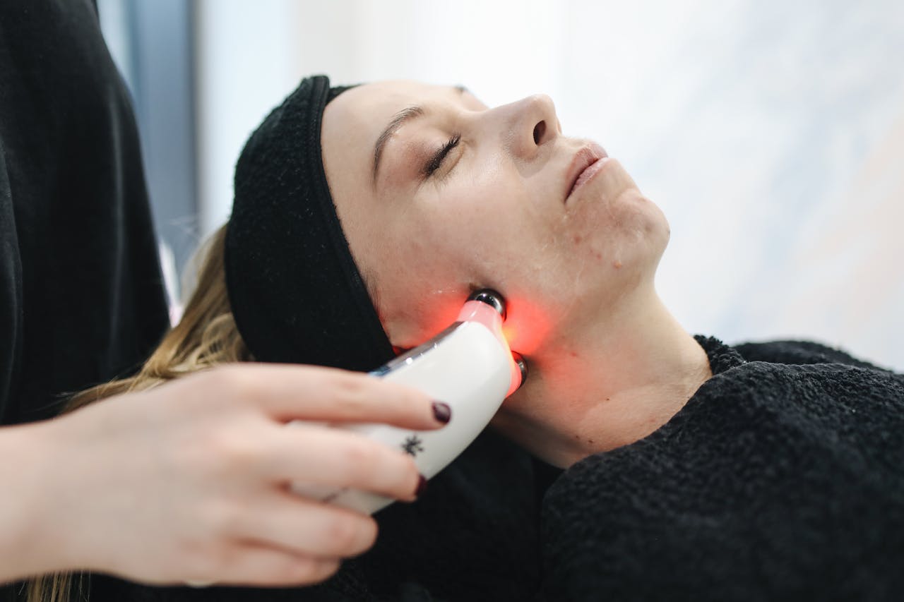 An adult woman receives a laser facial treatment in a modern skincare clinic.
