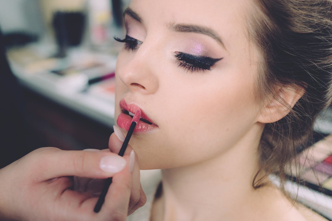 Close-up of an elegant woman having makeup applied, highlighting fashion and beauty.